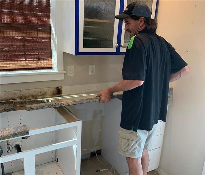 SERVPRO technician with boards from kitchen cabinet