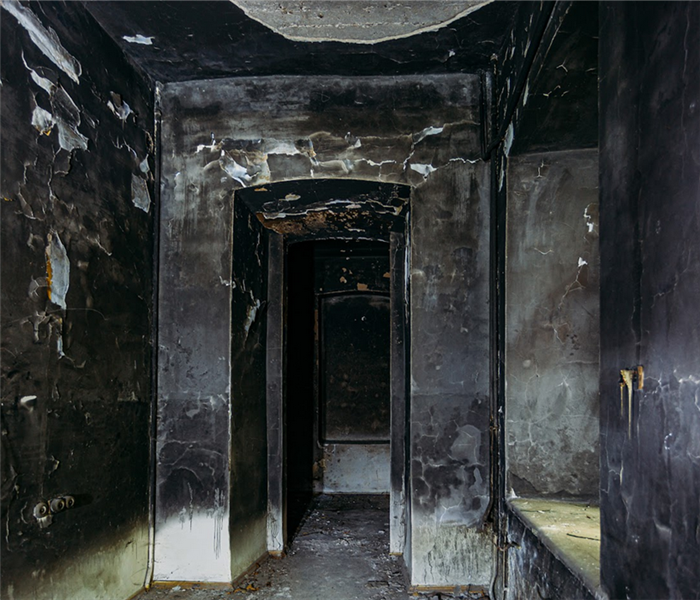 a fire damaged hallway with soot covering the burned walls
