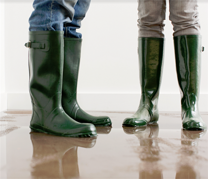 people standing in rain boots in a flooded room