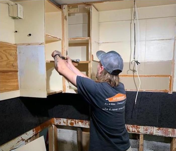SERVPRO technician removing mold damaged kitchen cabinets